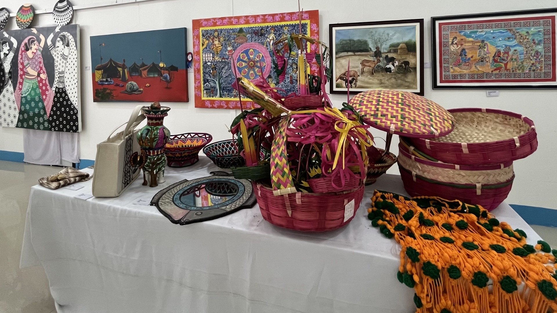 An embellishment of Mithila culture, featuring household items made of bamboo and Mithila (Madhubani) paintings in the back. Mithila art is known for its colorful designs and meticulous patterns.